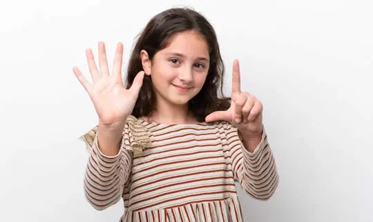 Young girl holding up seven fingers, the age of a first orthodontic check
